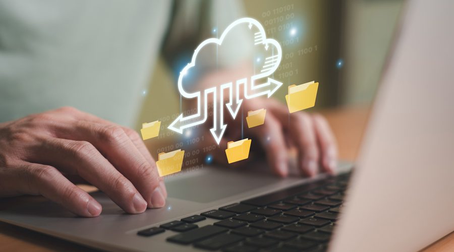 Hands typing on laptop with animated cloud syncing folders — automated, encrypted cloud backup and restore services by McNallan Technology for Minnesota enterprises