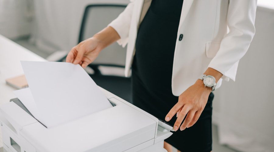 Businesswoman retrieving printed documents from a reliable office printer in a modern Minneapolis office